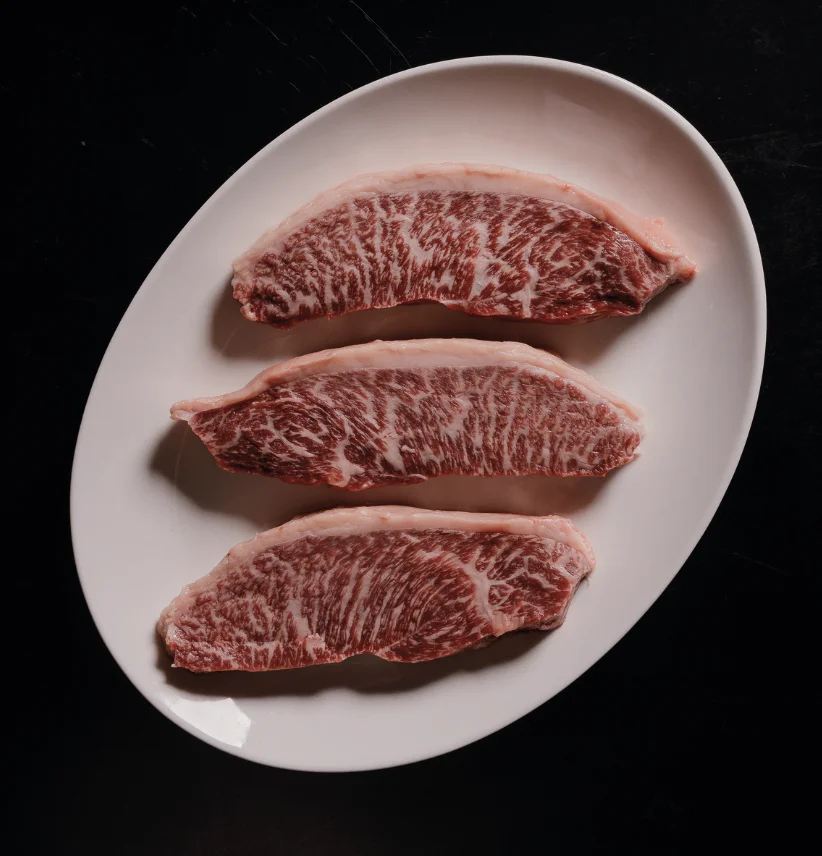 Three ICON Wagyu cuts showing fine intramuscular marbling on a white plate